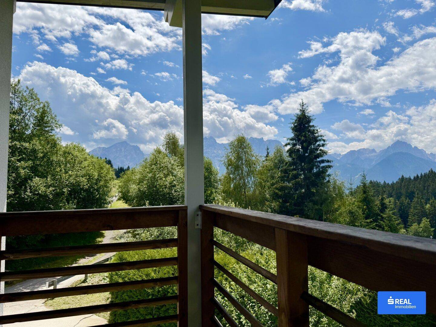 Balkon mit atemberaubendem Blick auf die umliegende Berglandschaft und grüne Wälder.