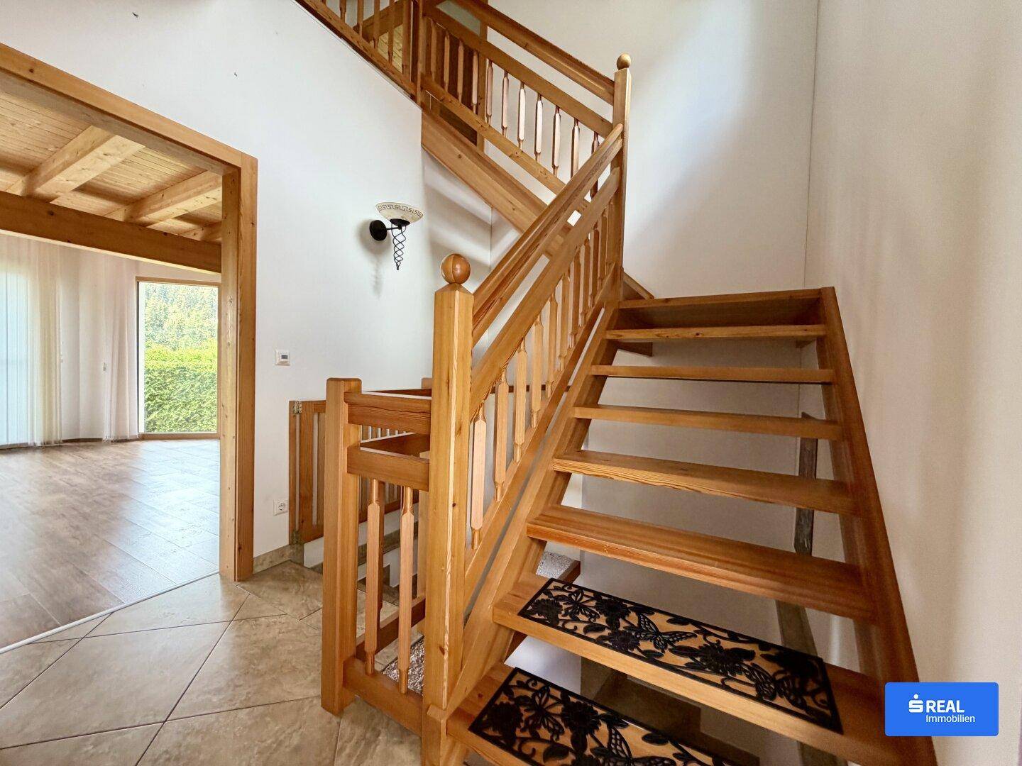 Massive Holztreppe im Flur mit Fliesenboden und Zugang zu weiteren Räumen.