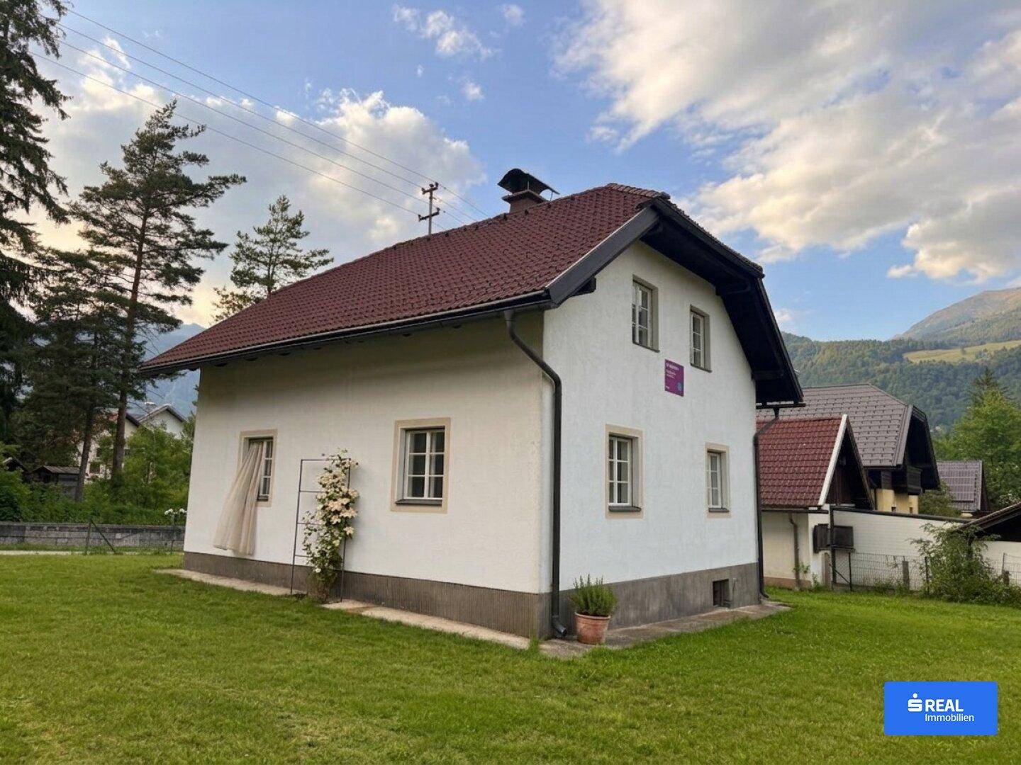 Ansicht des Hauses von der Seite mit gepflegtem Rasen und Blick auf die umliegende Natur.