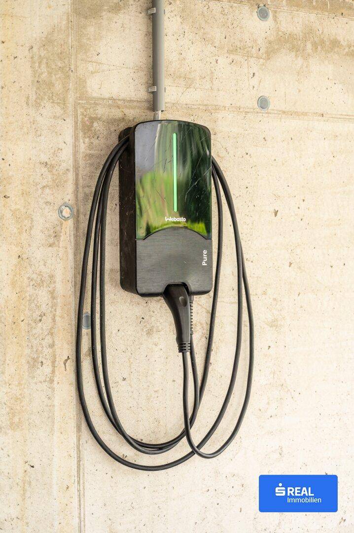 Wandmontierte Ladestation für Elektrofahrzeuge an einer Betonwand, bereit zur Nutzung.