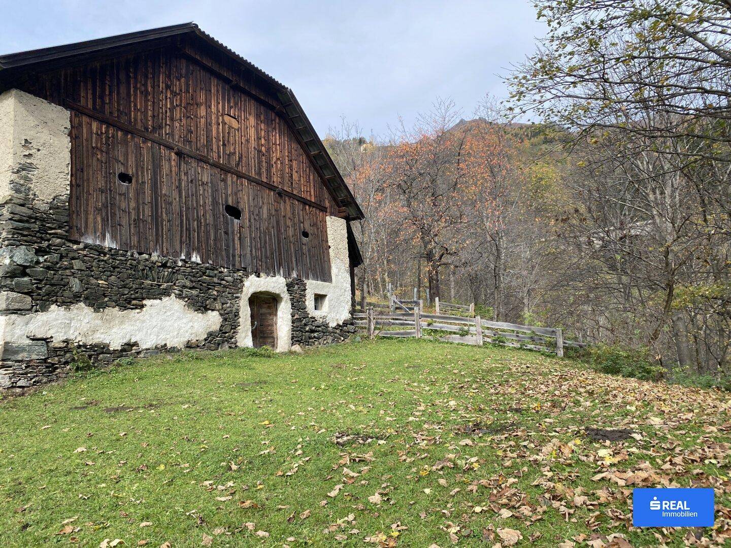 Rustikales Bauernhaus mit Holzwänden, Steinfundament und einfacher Holztür.