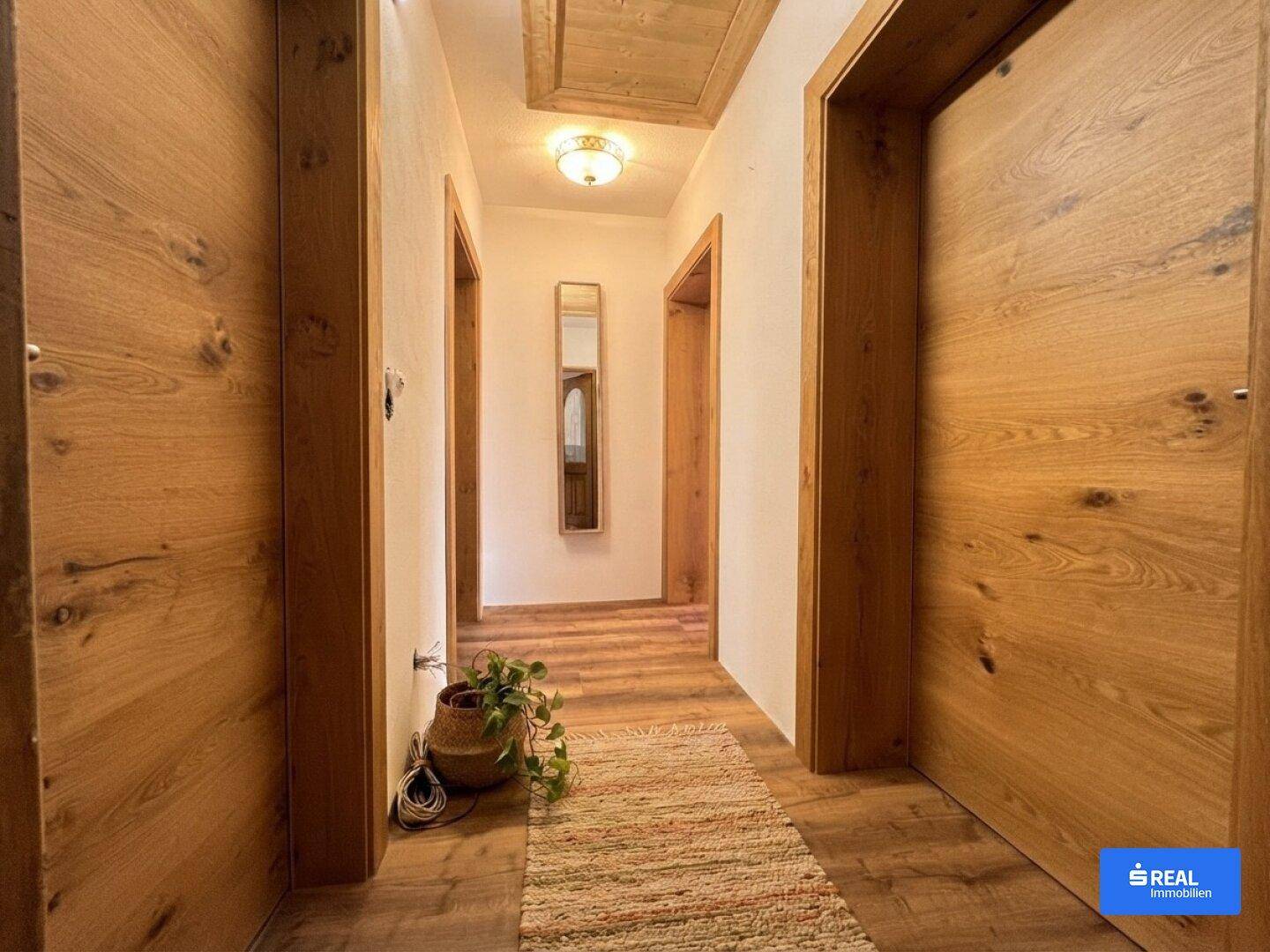 Gemütlicher Flur mit Holzboden und Holztüren, der zu weiteren Räumen führt.