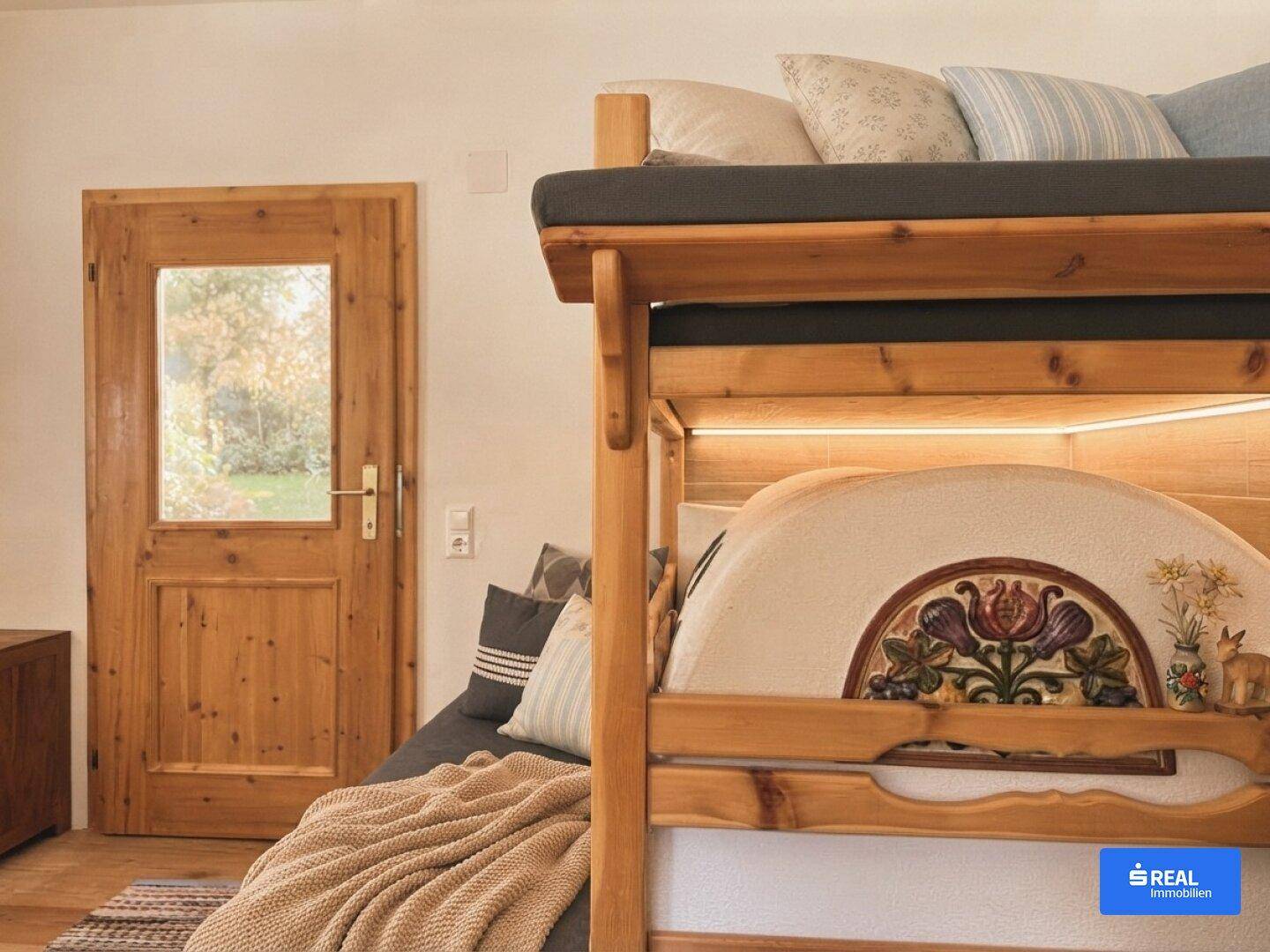 Schlafzimmer mit traditionellem Etagenbett aus Holz und einer Holztür mit Glasausschnitt.