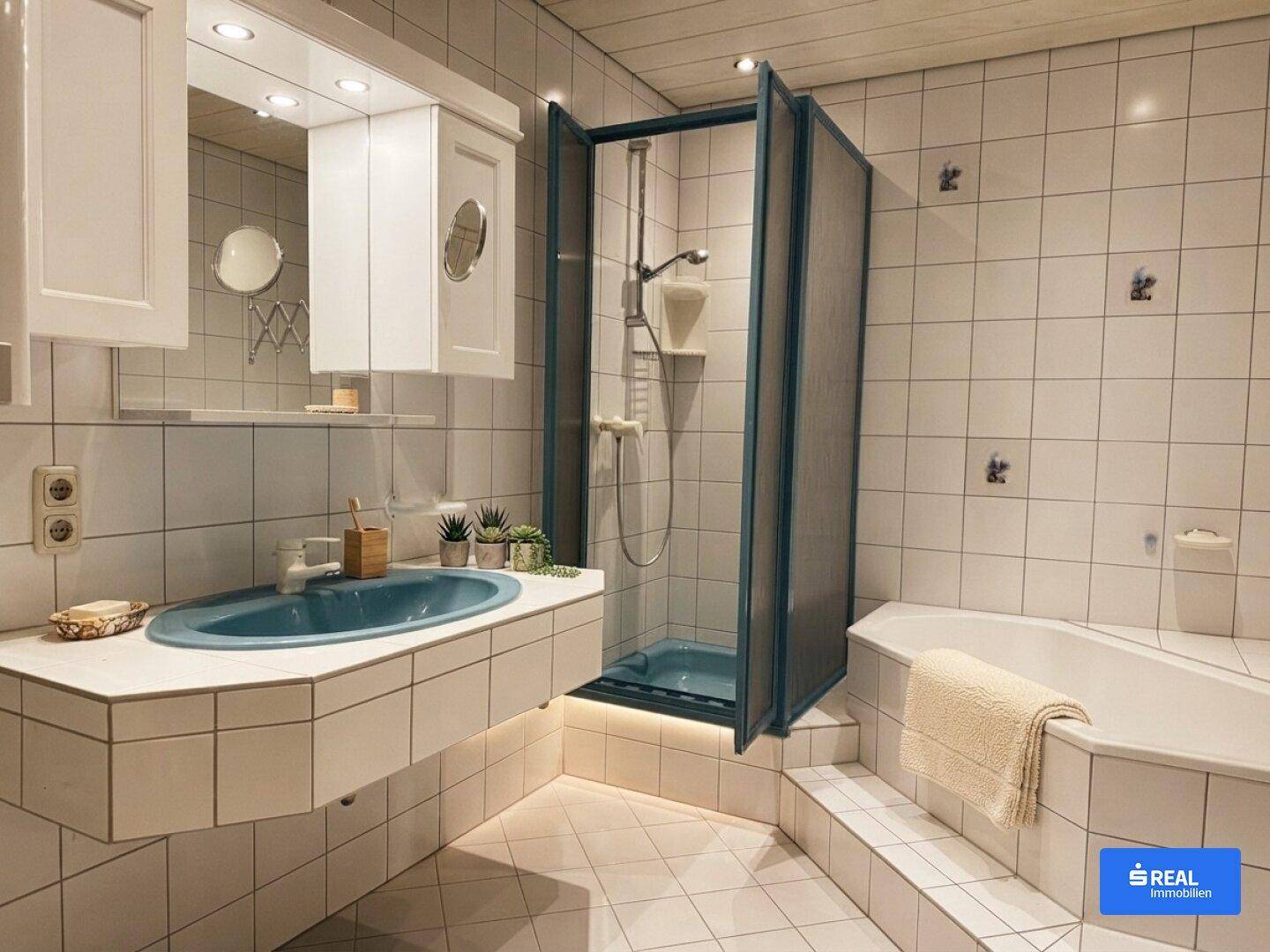 Gefliestes Badezimmer mit Duschkabine, Eckbadewanne und einem einzelnen Waschbecken mit Spiegelschrank.
