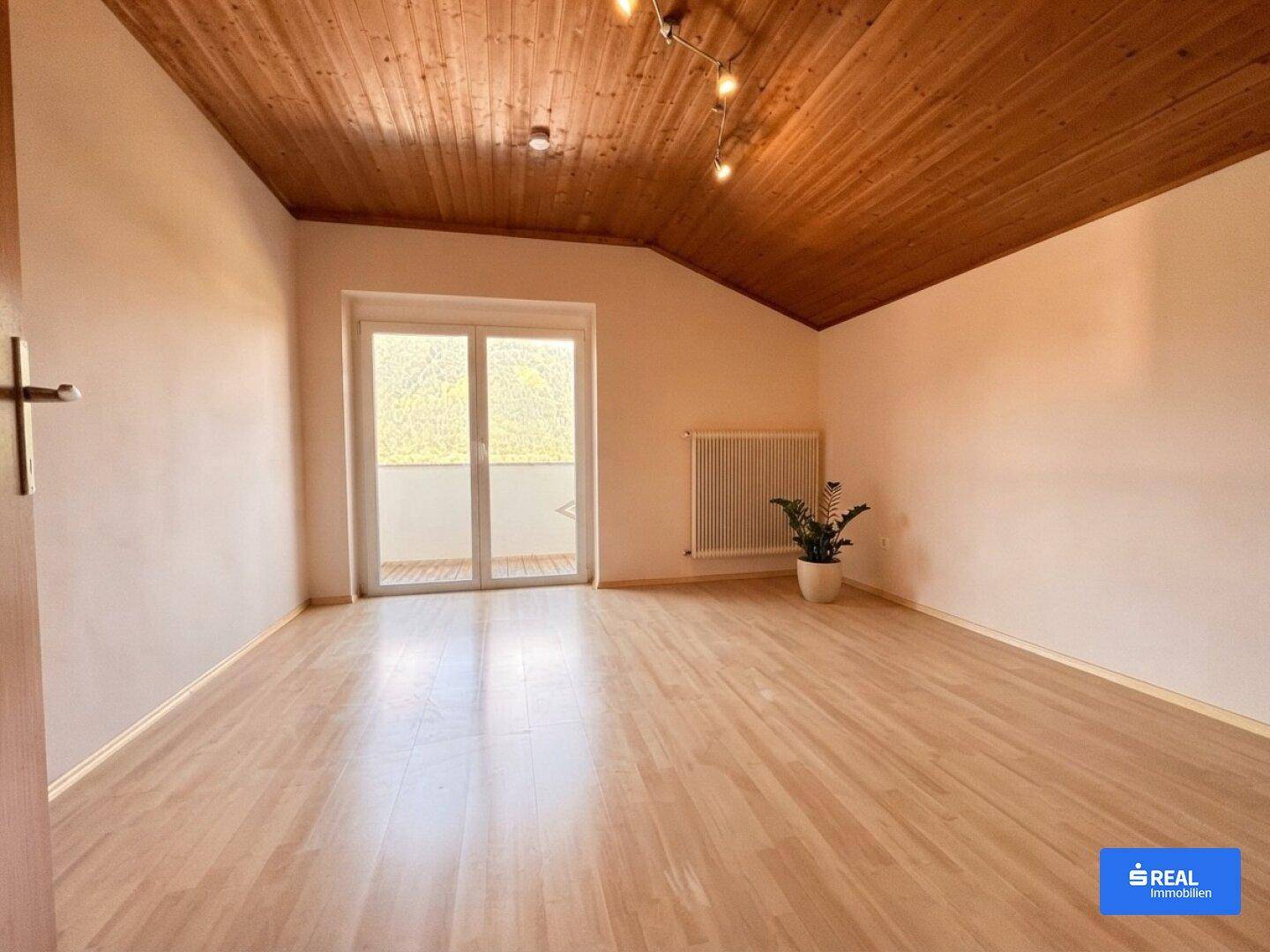 Geräumiges Schlafzimmer mit Holzboden, Holzdecke und Zugang zum Balkon mit Bergblick.