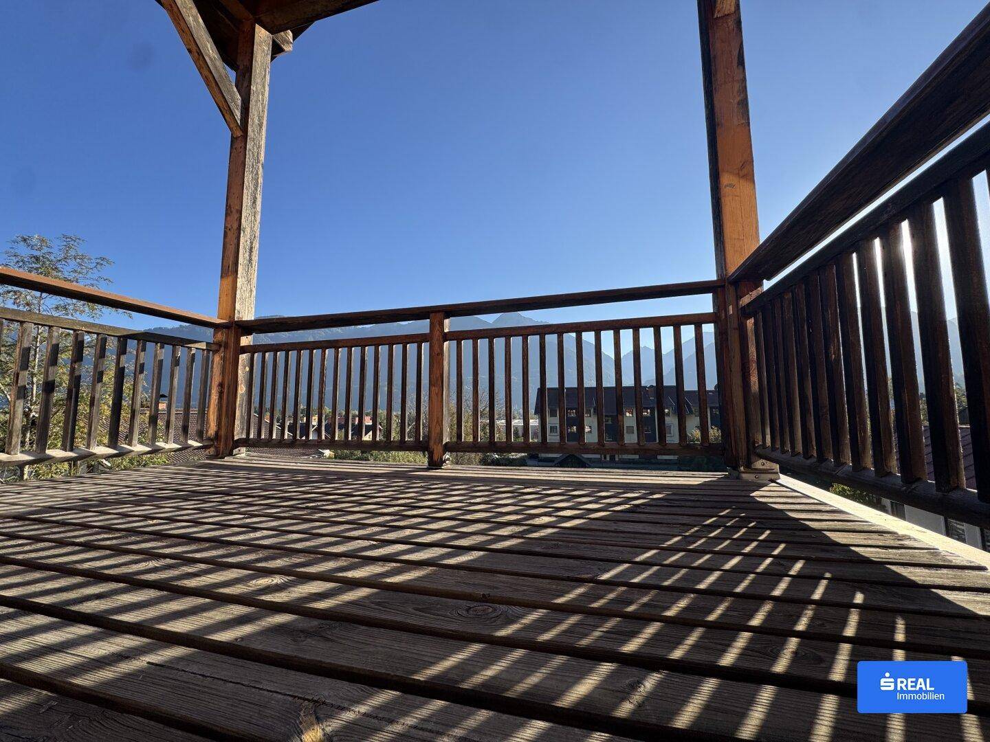 Geräumiger Holzbalkon mit rustikalem Geländer und weitem Blick auf die umliegende Berglandschaft.