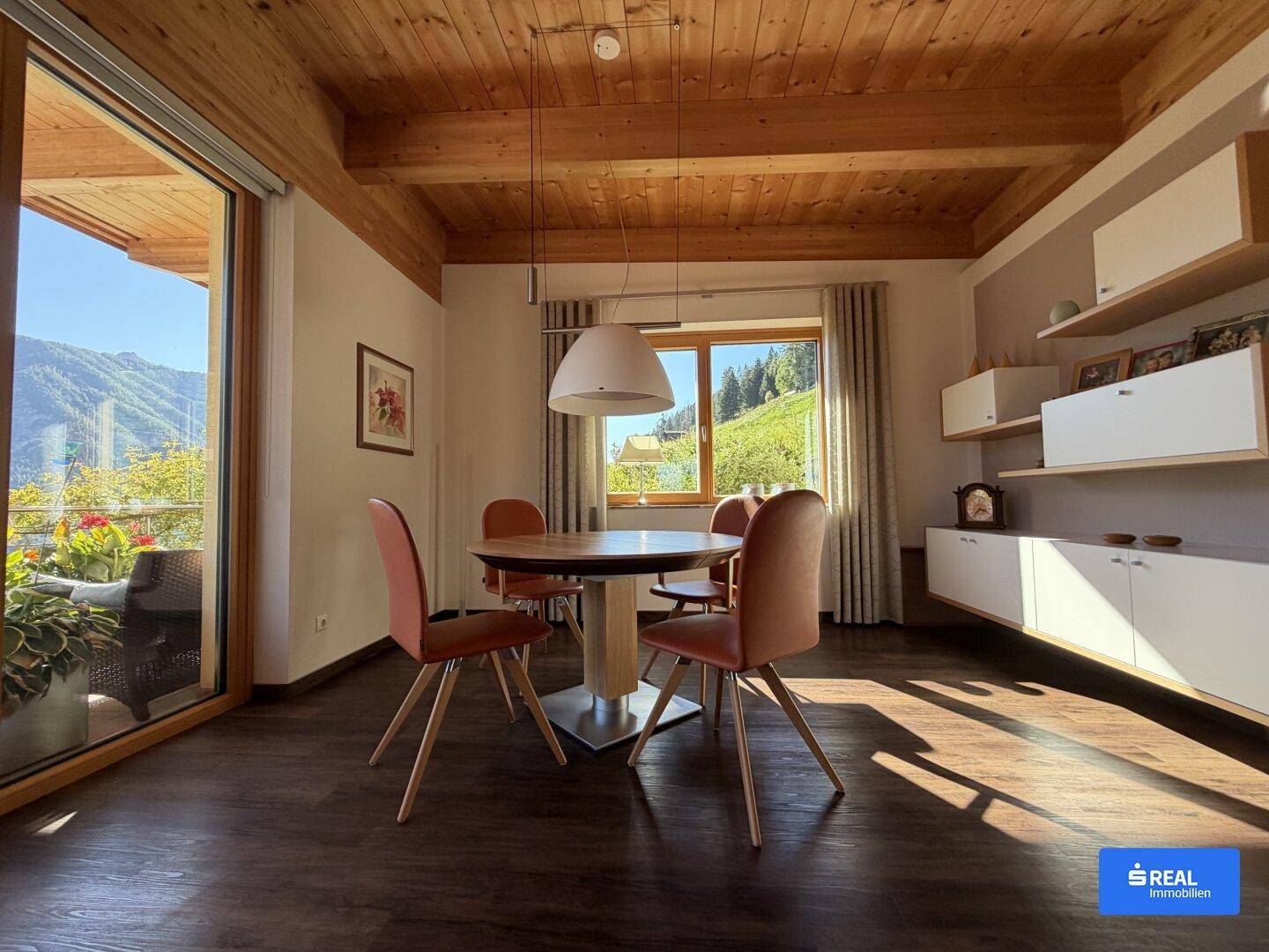 Heller Essbereich mit modernem Holztisch, Designerstühlen und Zugang zu einem sonnigen Balkon.