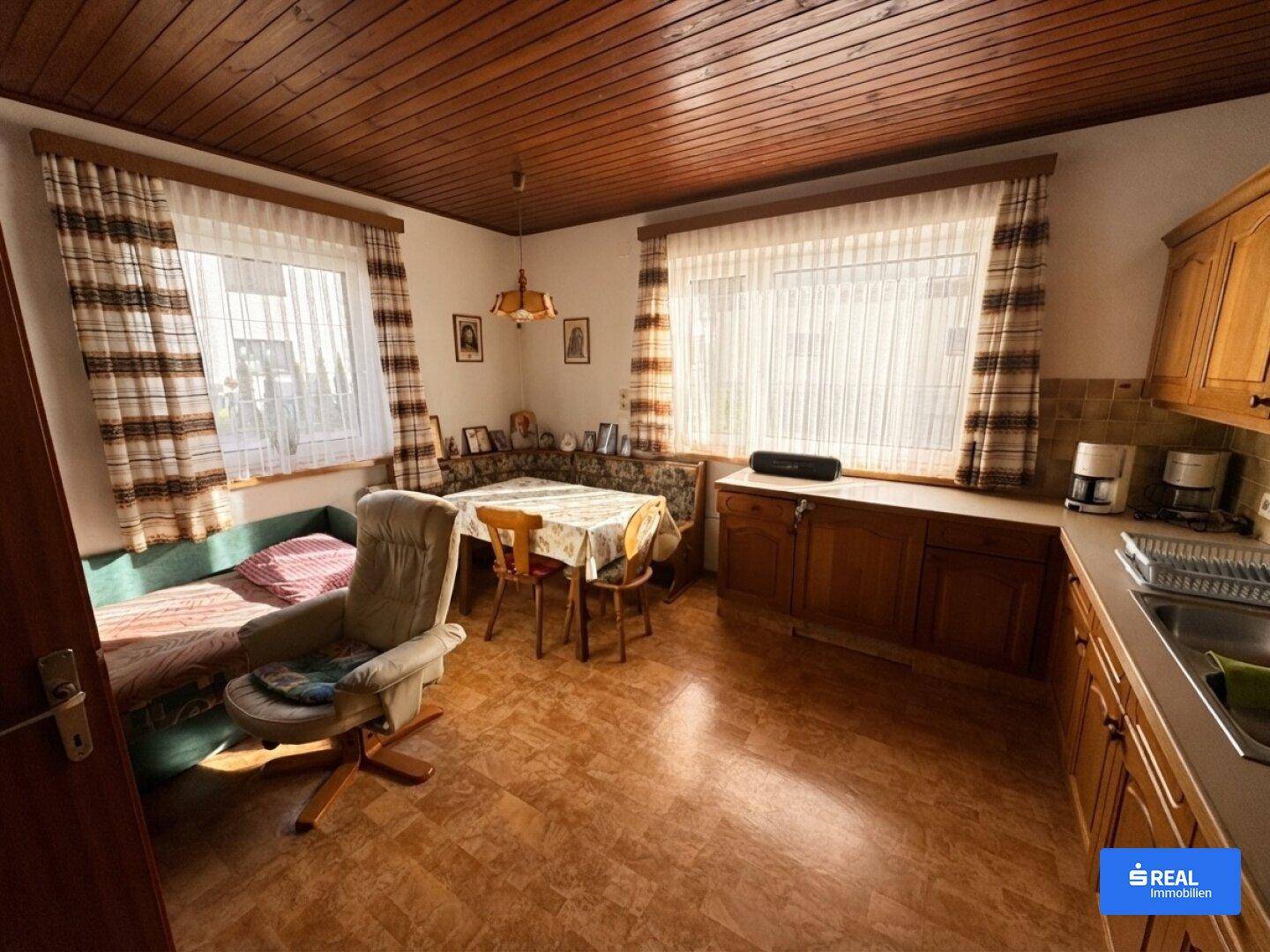 Gemütliche Wohnküche mit traditionellen Holzmöbeln und Essbereich am Fenster.