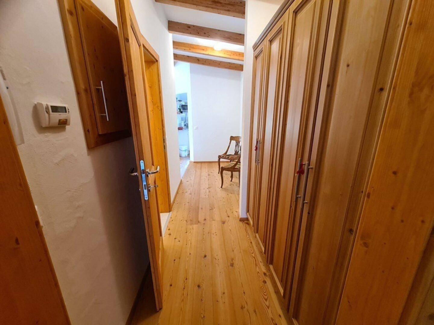 Heller Flur mit Einbauschränken aus Holz und durchgehendem Holzdielenboden.