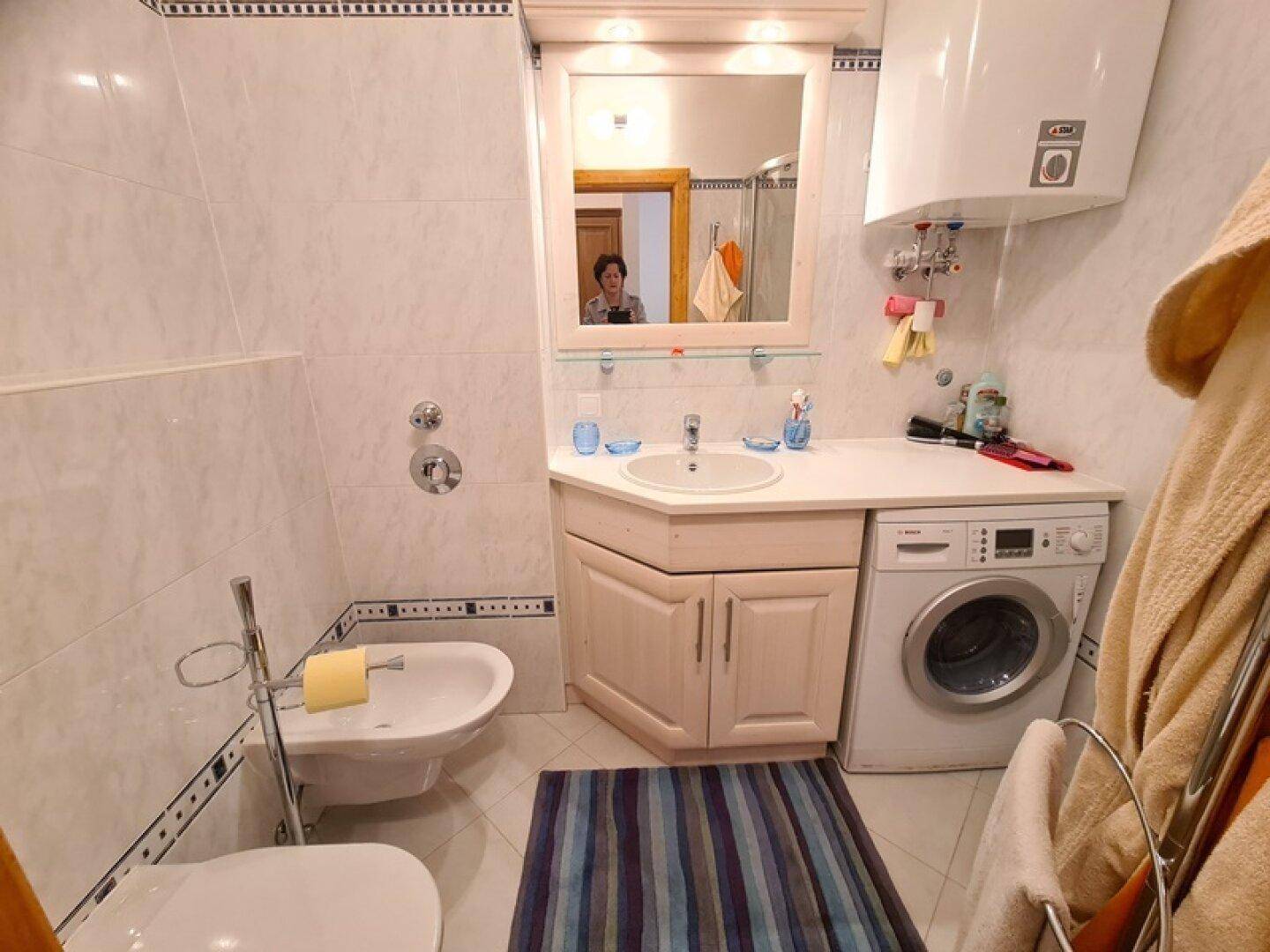Funktionales Badezimmer mit Waschmaschine, Bidet, Toilette und weiß-blauen Fliesen.