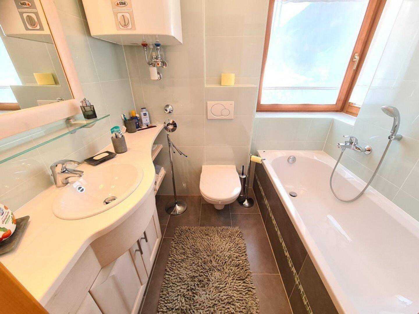 Badezimmer mit Badewanne, Einzelwaschbecken und Dachfenster, das viel natürliches Licht hereinlässt.