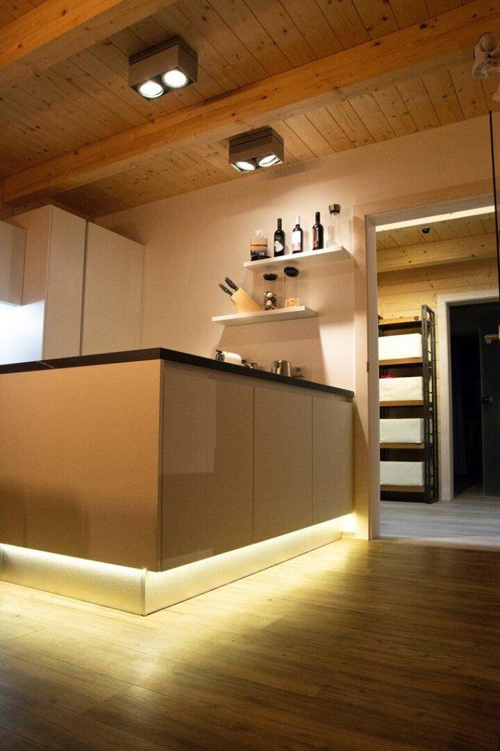 Moderne Kücheninsel mit integrierter Beleuchtung und dunkler Arbeitsplatte.