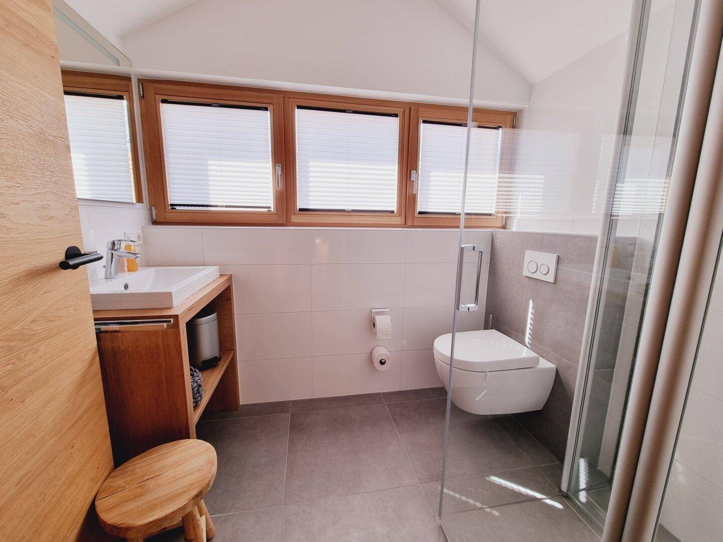 Helles Badezimmer im Dachgeschoss mit Schrägdecke, Fenster und ebenerdiger Dusche.