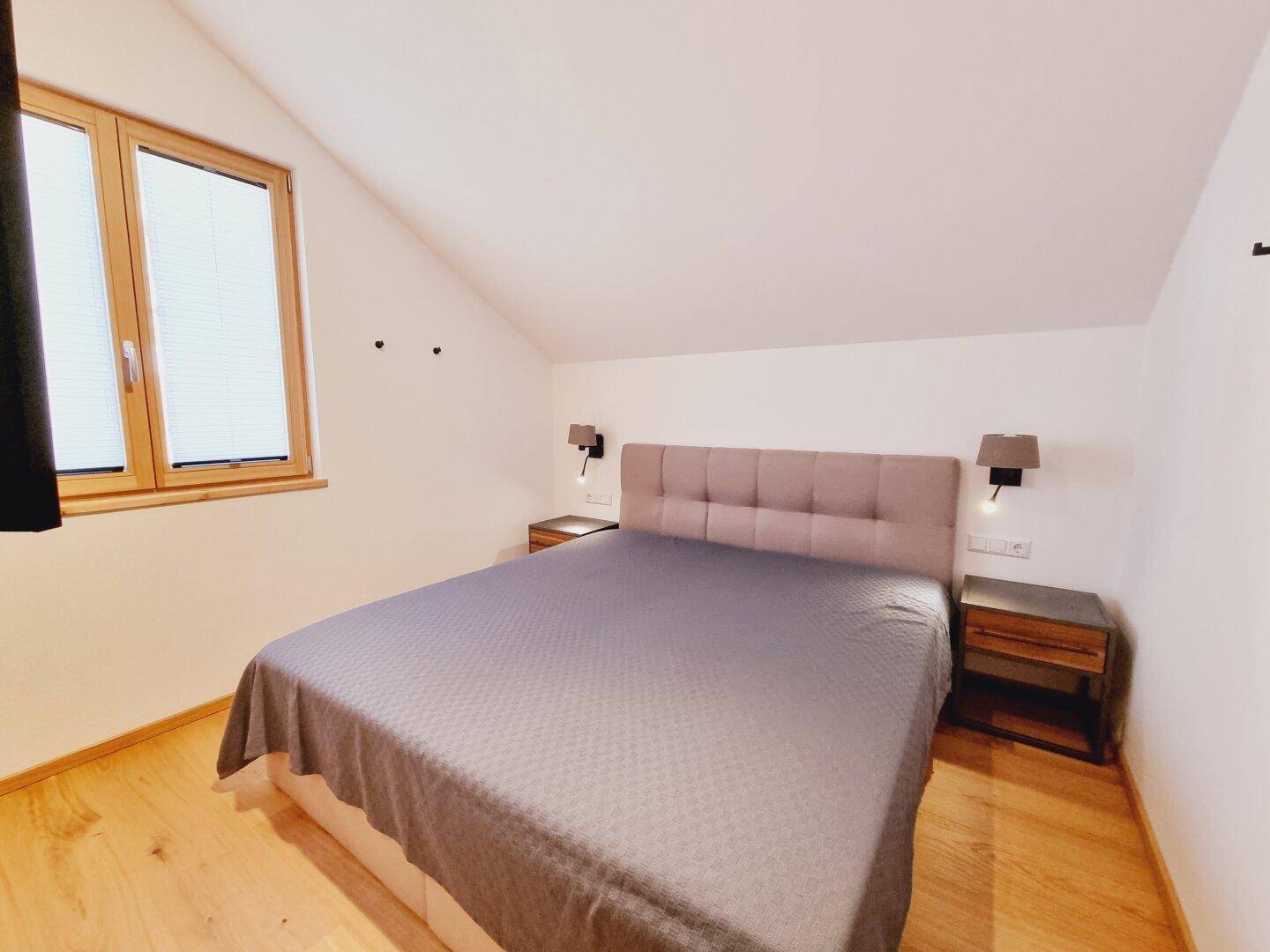 Gemütliches Schlafzimmer im Dachgeschoss mit Doppelbett, Holzboden und Fenster.