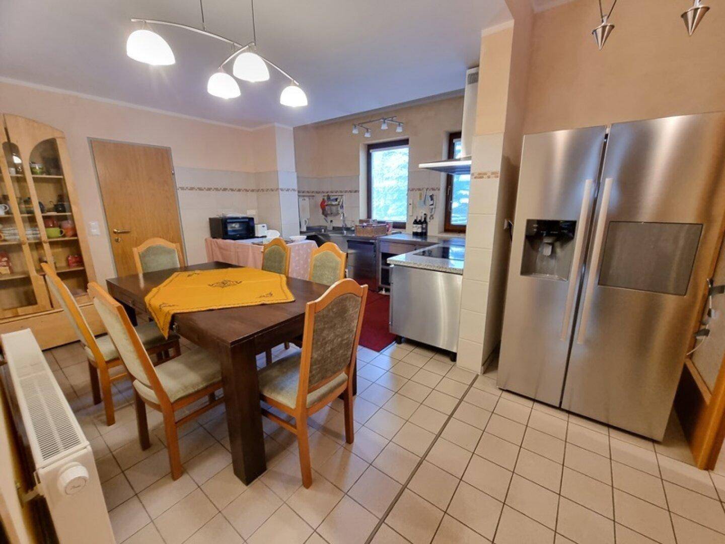Geräumige Küche mit Essbereich, großem Kühlschrank und Fliesenboden.
