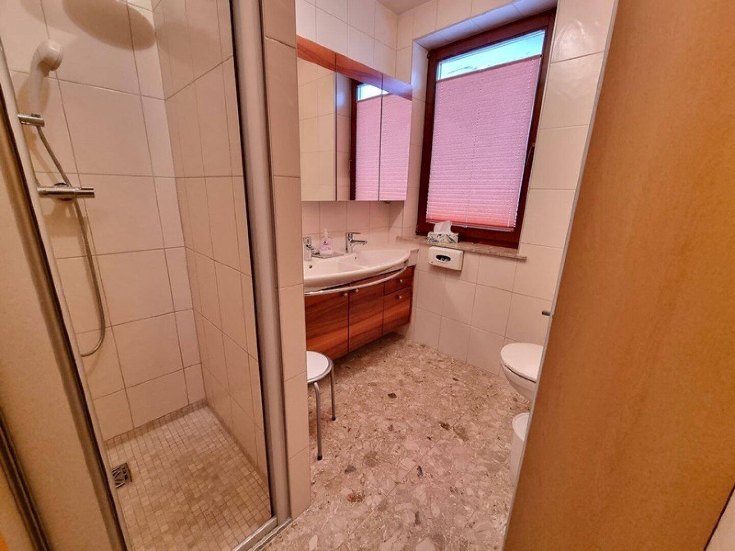 Modernes Badezimmer mit Dusche, Einzelwaschbecken und Fenster für Tageslicht.