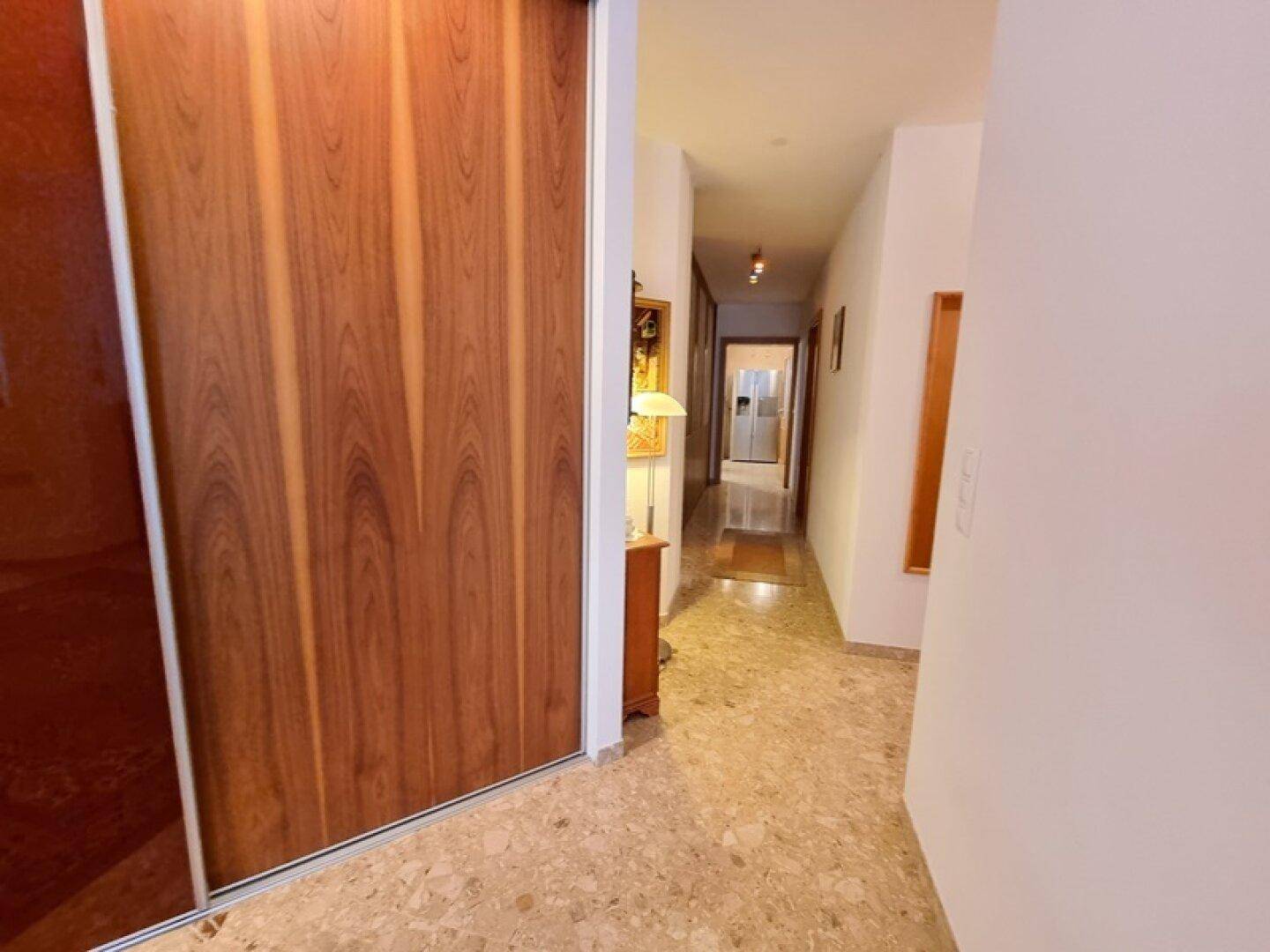 Langer Flur mit Holzschiebetüren und Steinboden, der zu weiteren Räumen führt.