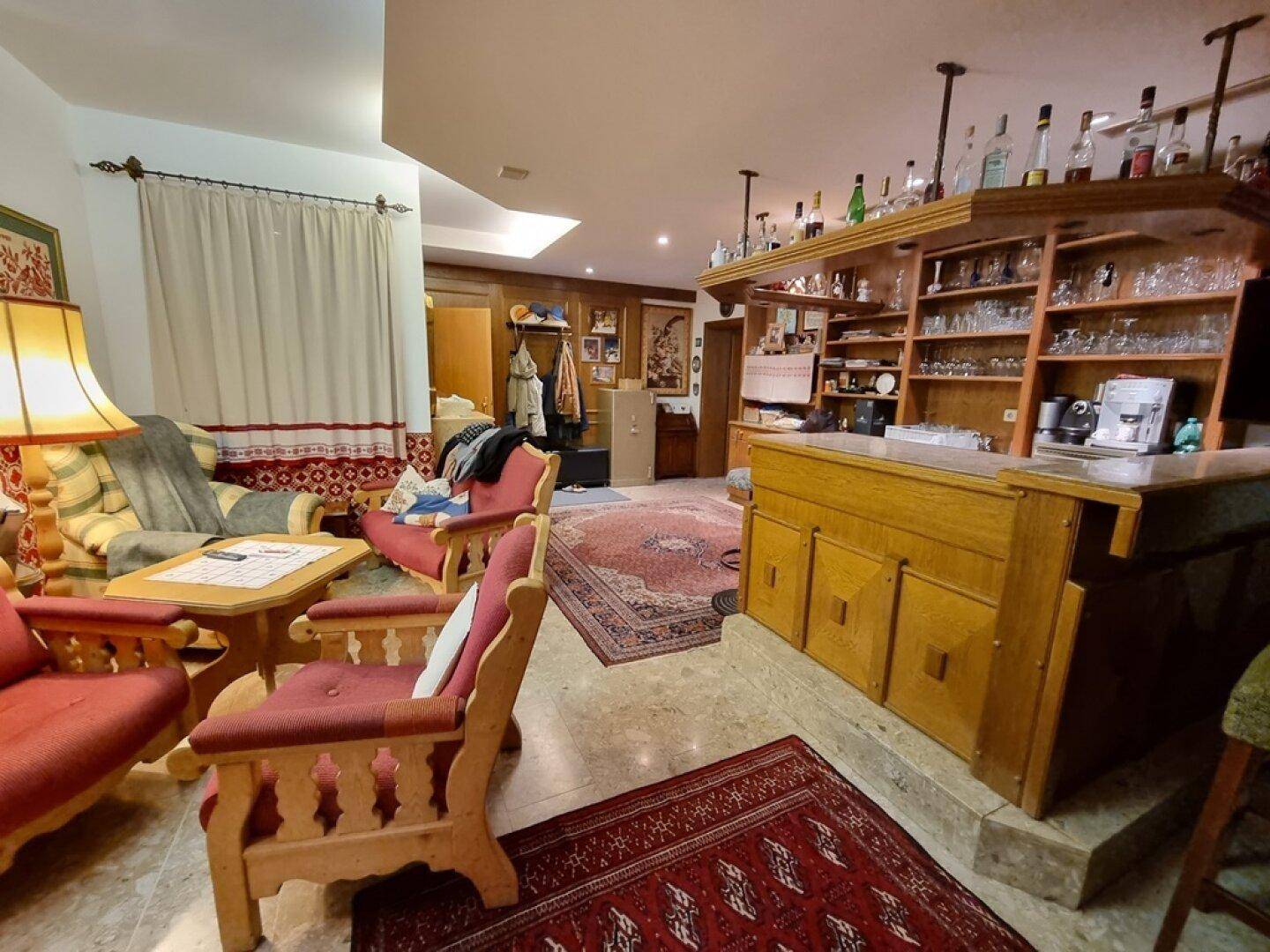 Wohnbereich mit Bar, traditionellen Holzmöbeln und Teppichen, ideal für gesellige Abende.
