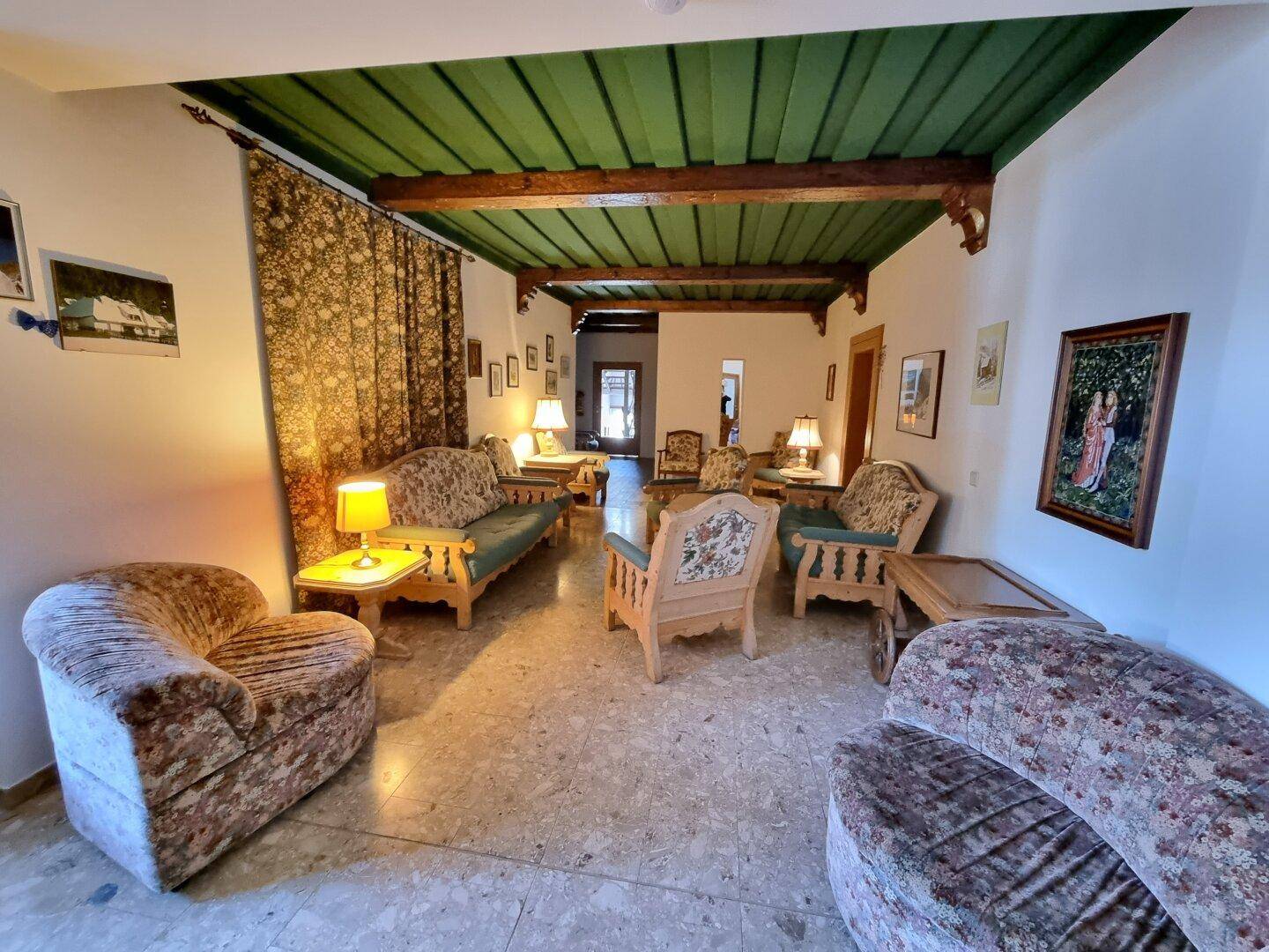 Rustikales Wohnzimmer mit Holzbalkendecke, traditionellen Möbeln und Teppichen.