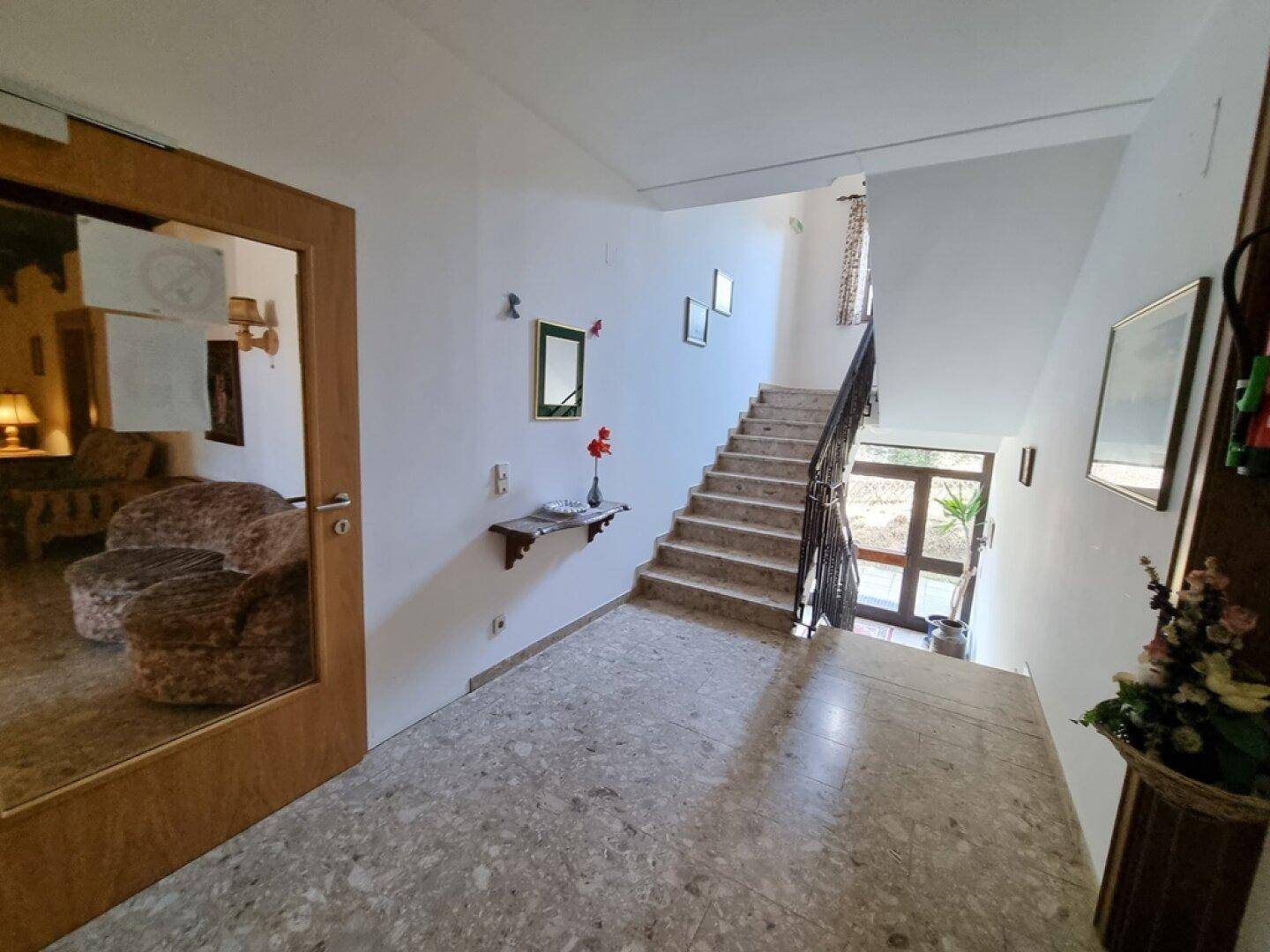 Eingangsbereich mit Treppe und Steinboden, der zu den oberen Etagen führt.