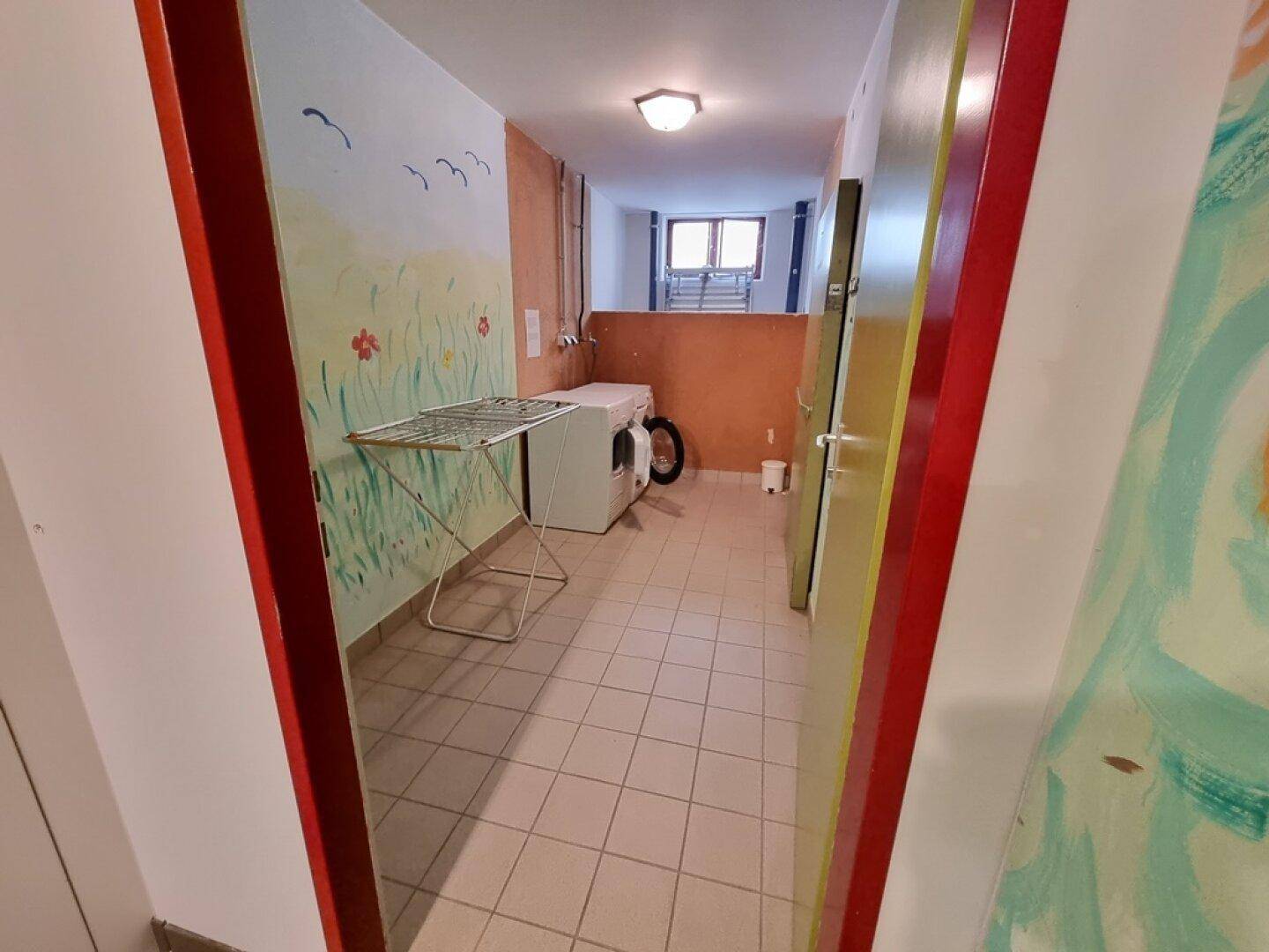 Waschküche mit Waschmaschine, Trockner und Wäscheständer, funktional eingerichtet.