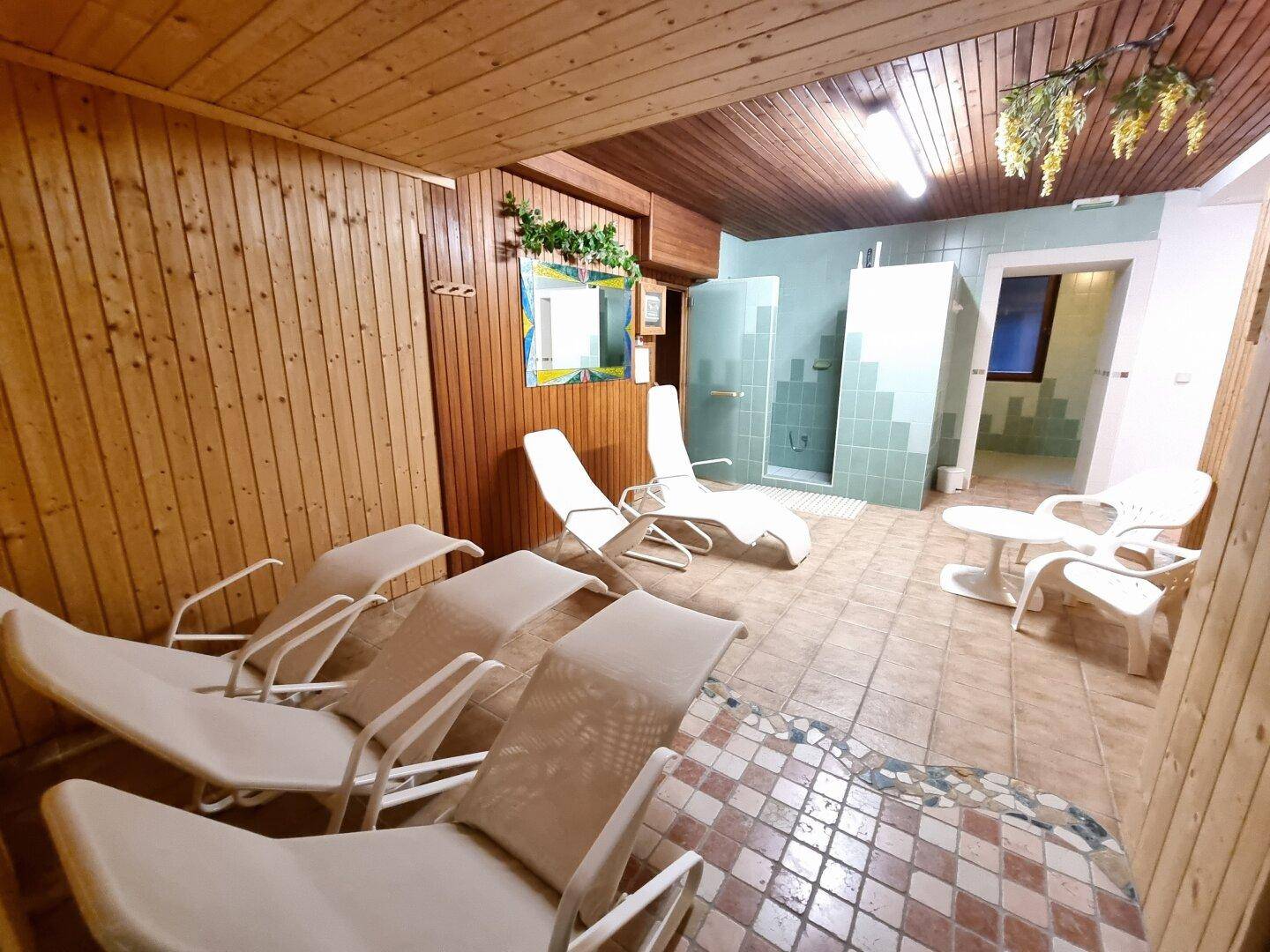 Wellnessbereich mit Liegestühlen, Holzvertäfelung und Duschbereich, ideal zur Erholung.