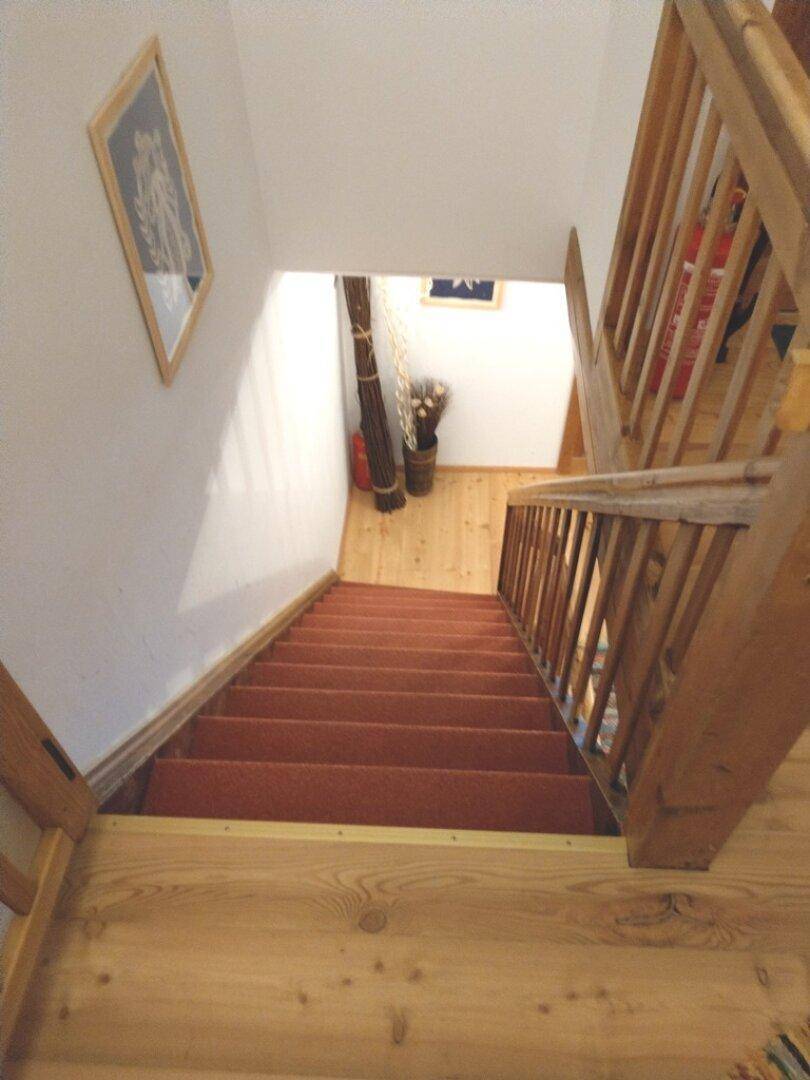 Holztreppe mit Teppichboden, die in die untere Etage führt.