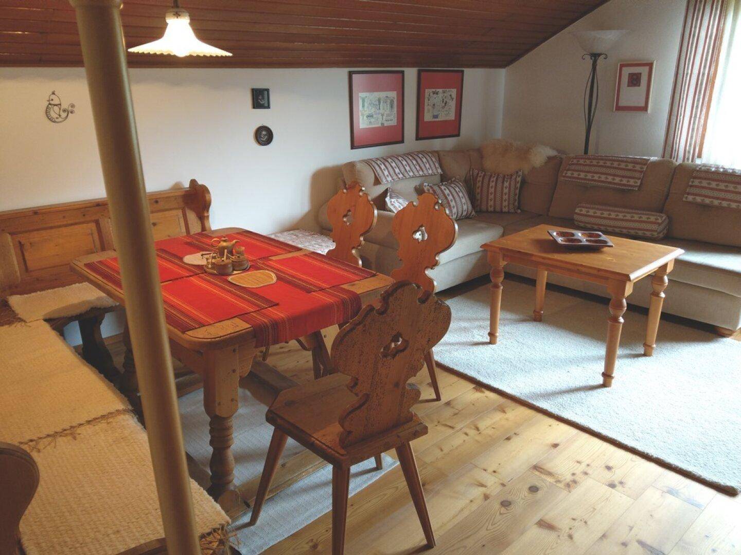 Wohn- und Essbereich im Dachgeschoss mit Holzbalkendecke und rustikalen Möbeln.