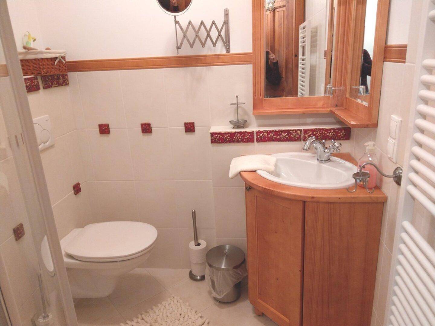 Badezimmer mit Waschbecken, WC und Spiegel, gefliest in hellen Tönen.