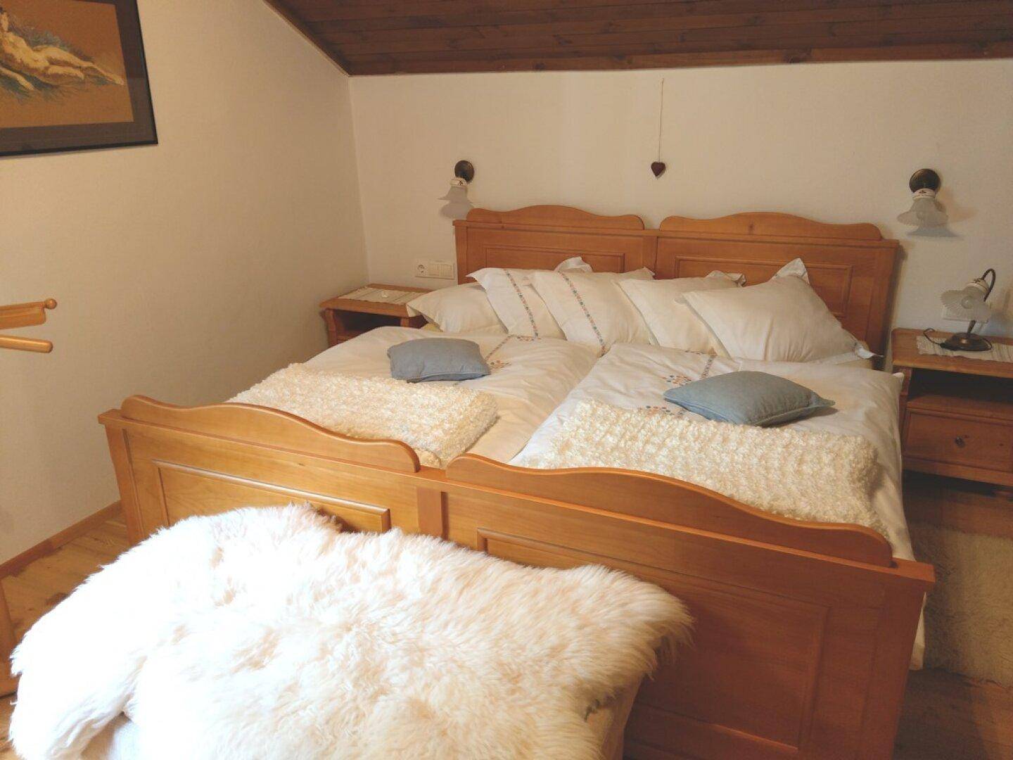Schlafzimmer im Dachgeschoss mit Doppelbett, Holzmöbeln und schräger Decke.