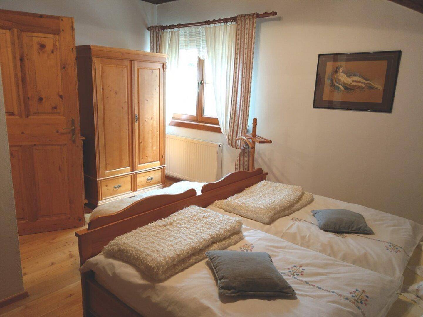 Schlafzimmer im Dachgeschoss mit zwei Einzelbetten, Kleiderschrank und schräger Decke.