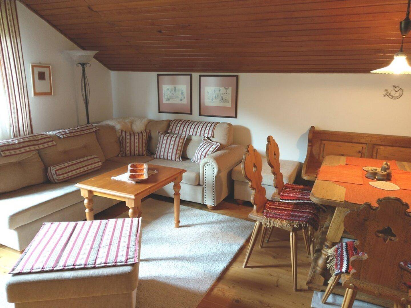 Wohn- und Essbereich im Dachgeschoss mit Holzbalkendecke und traditionellen Möbeln.