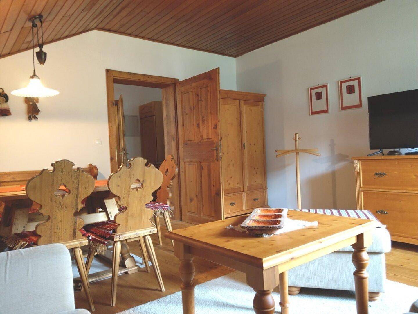 Wohn- und Essbereich im Dachgeschoss mit Holzbalkendecke und traditionellen Möbeln.