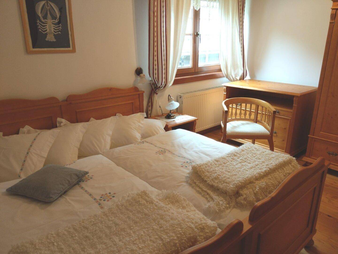 Schlafzimmer im Dachgeschoss mit Doppelbett, Holzmöbeln und Blick nach draußen.