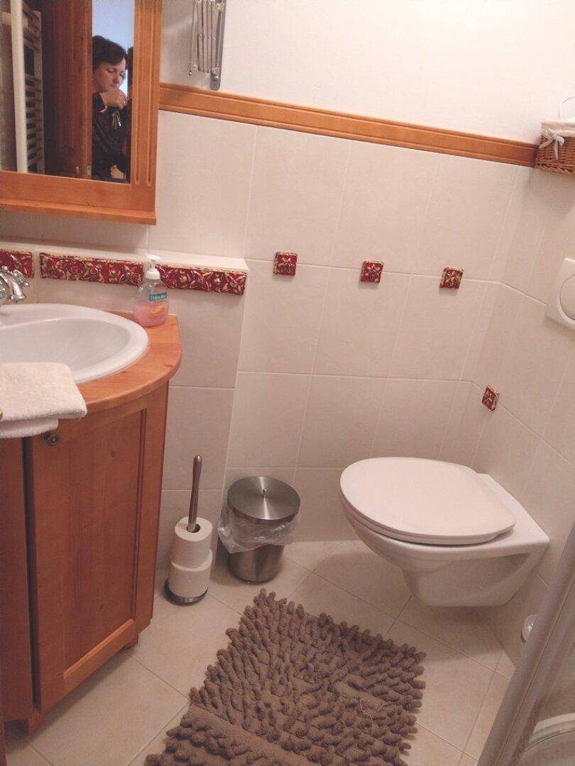 Badezimmer mit Waschbecken, WC und Spiegel, gefliest in hellen Tönen.