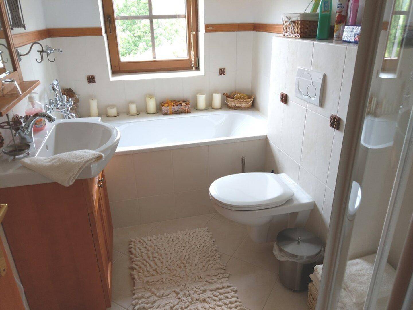 Badezimmer mit Badewanne, WC und Waschbecken, gefliest in hellen Tönen.