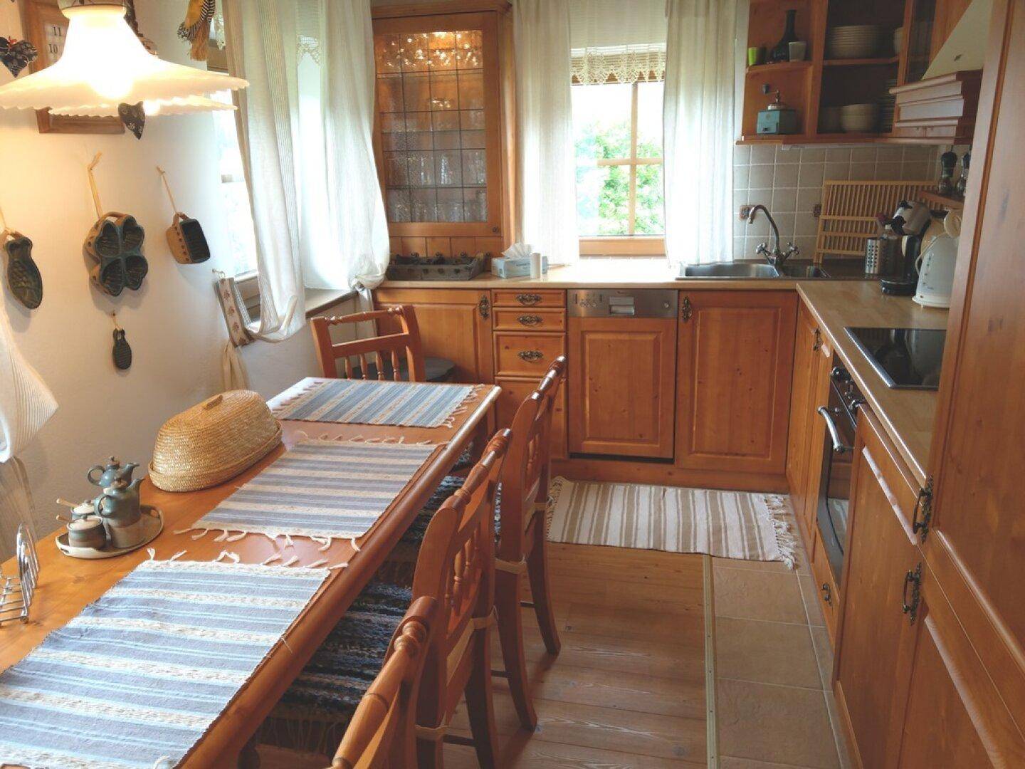 Rustikale Küche mit Holzeinbauten, Essbereich und Blick nach draußen.