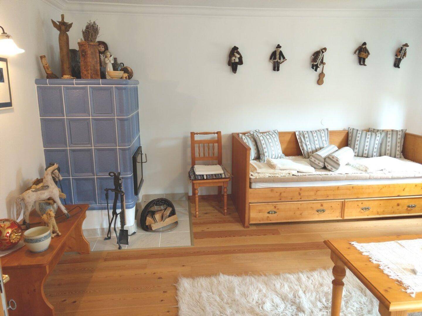 Wohnzimmer mit Kachelofen, Tagesbett und traditioneller Dekoration.