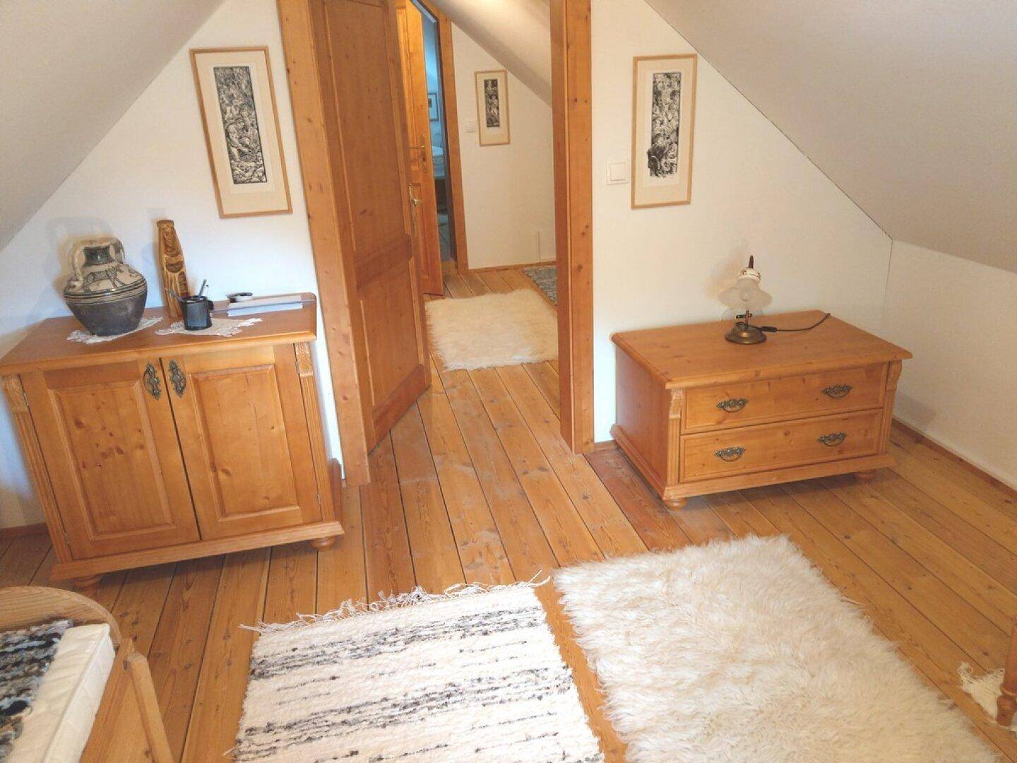 Flur im Dachgeschoss mit Holzboden, Kommode und Zugang zu weiteren Räumen.