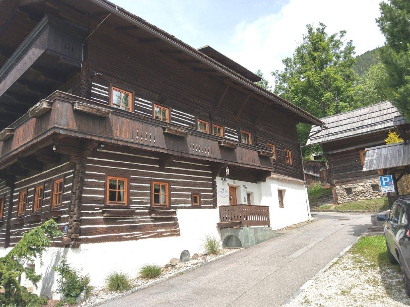 Traditionelles Holzhaus mit Balkonen und umliegender Natur.