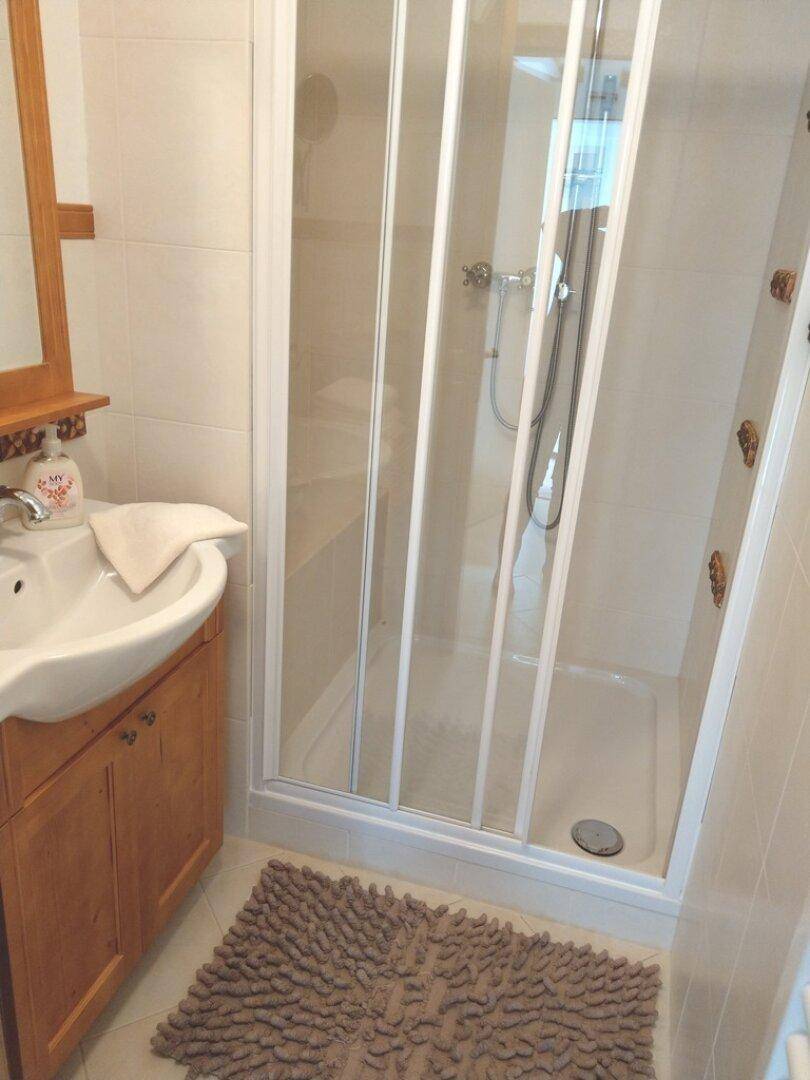 Badezimmer mit Duschkabine, Waschbecken und WC, gefliest in hellen Tönen.