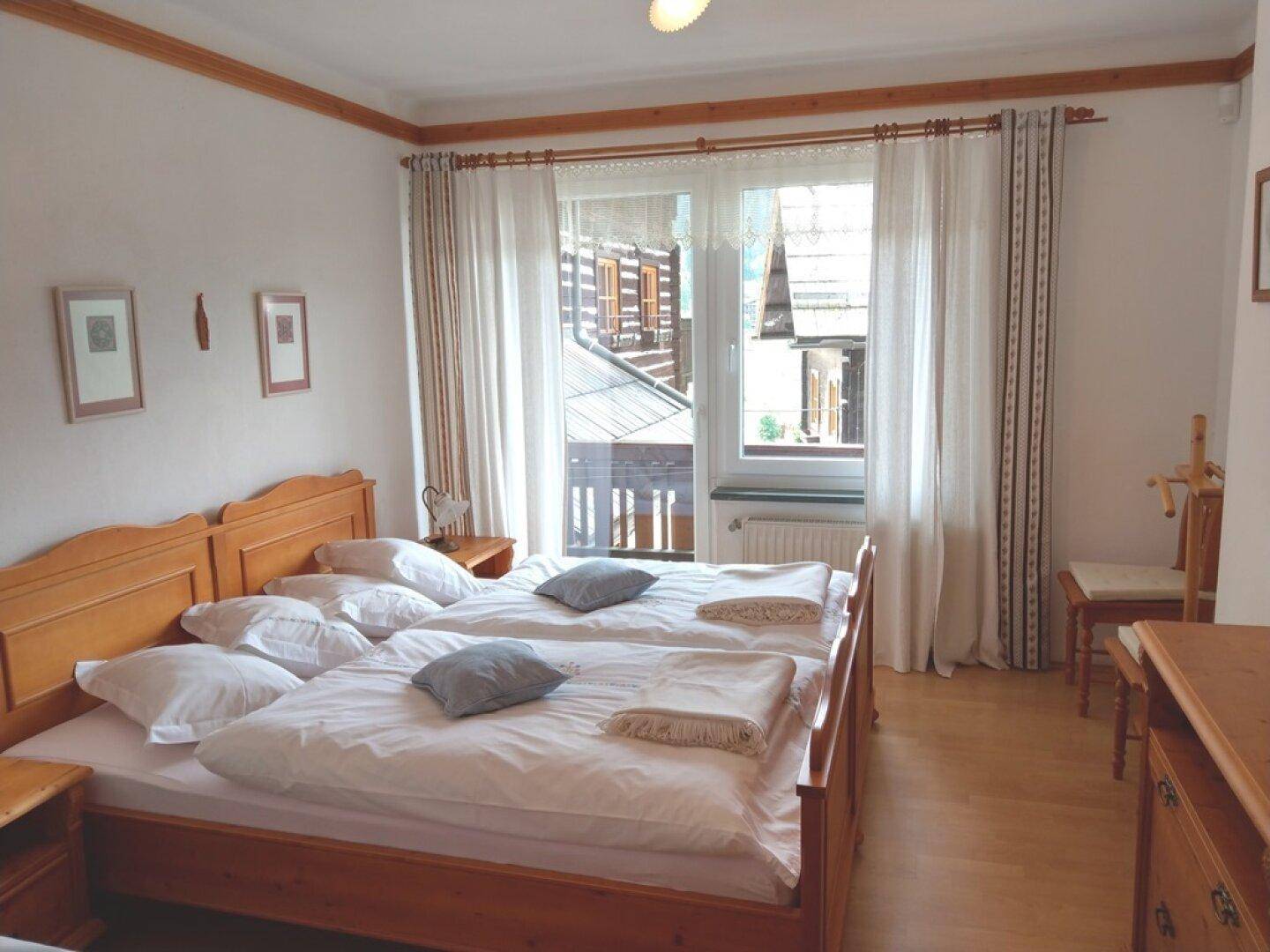Schlafzimmer mit Doppelbett, Balkonzugang und Blick auf die Umgebung.
