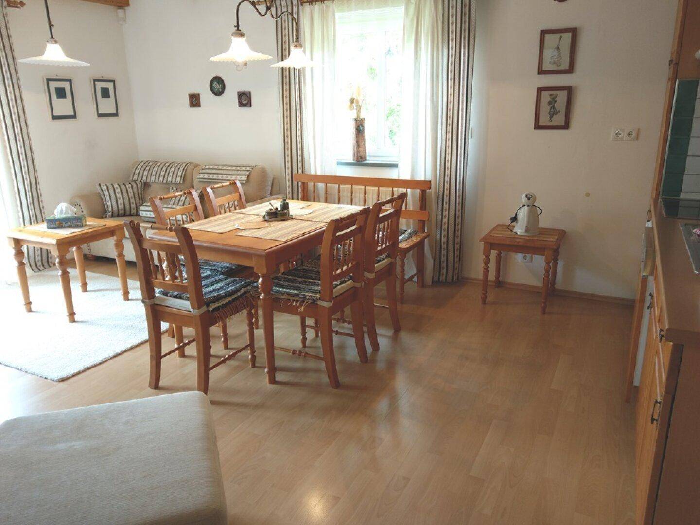 Offener Wohn- und Essbereich mit Küchenzeile, Holzboden und traditionellen Möbeln.