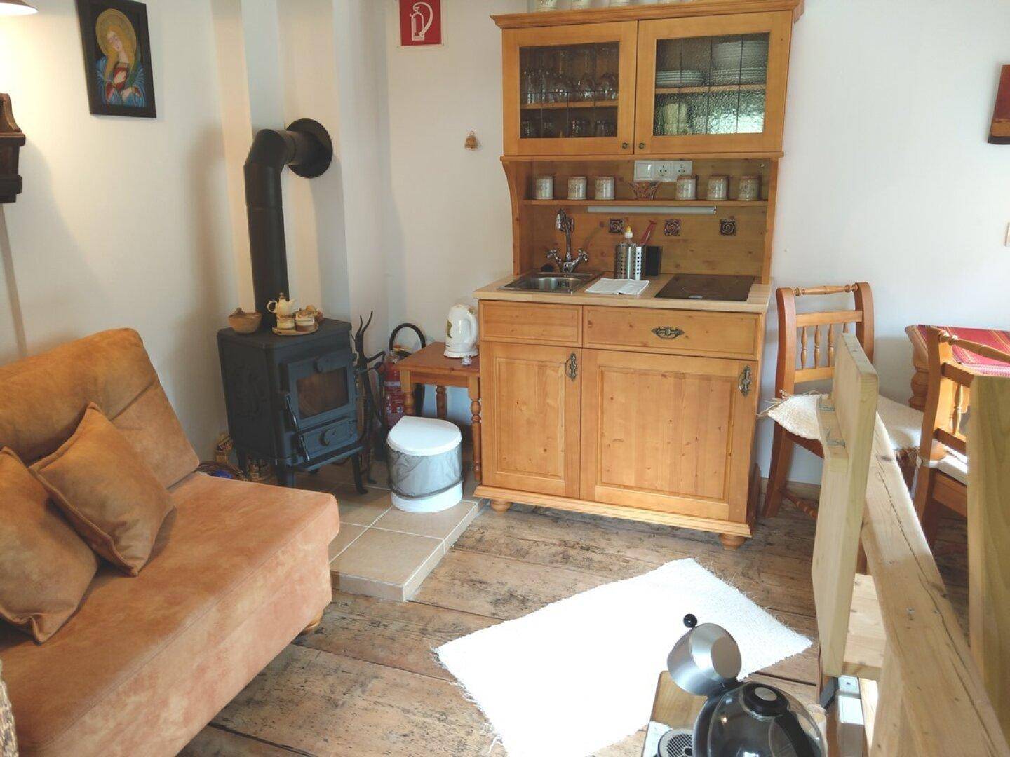 Kleiner Wohnbereich mit Küchenzeile, Holzofen und Sofa.