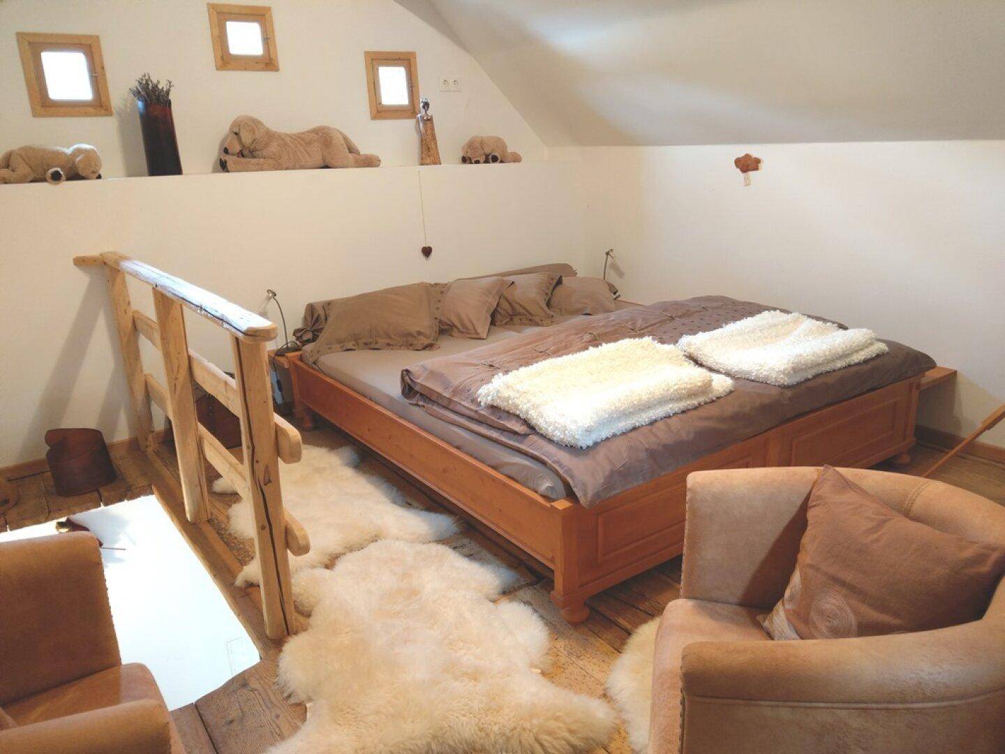Schlafzimmer im Dachgeschoss mit Doppelbett, schrägen Wänden und Holzboden.
