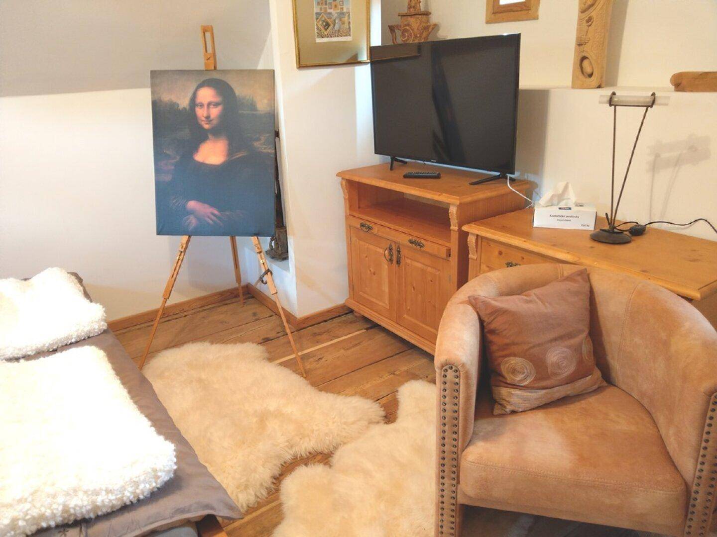 Schlafzimmer im Dachgeschoss mit Doppelbett, Fernseher und Sessel.