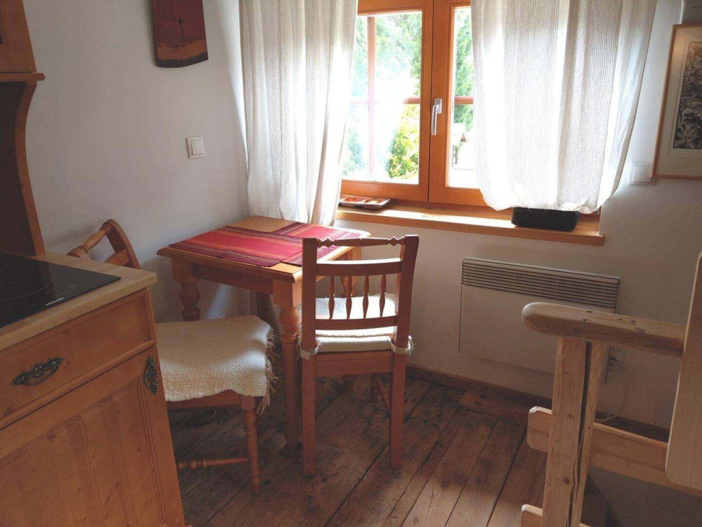 Kleine Küchenzeile mit Essbereich und Fenster, das viel Licht hereinlässt.