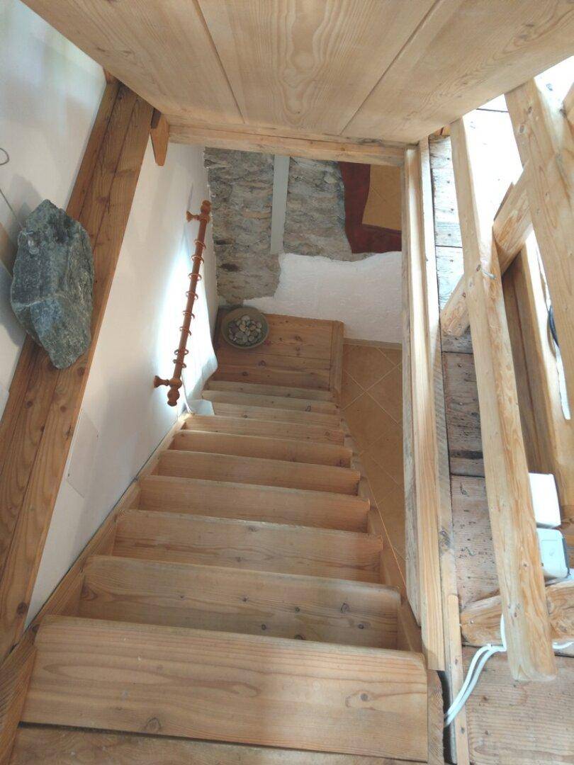 Holztreppe, die in den unteren Bereich führt, mit rustikalen Elementen.