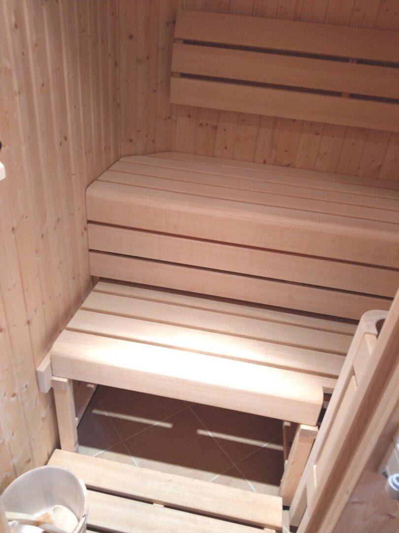 Sauna mit Holzbänken und Holzverkleidung, bereit zur Entspannung.