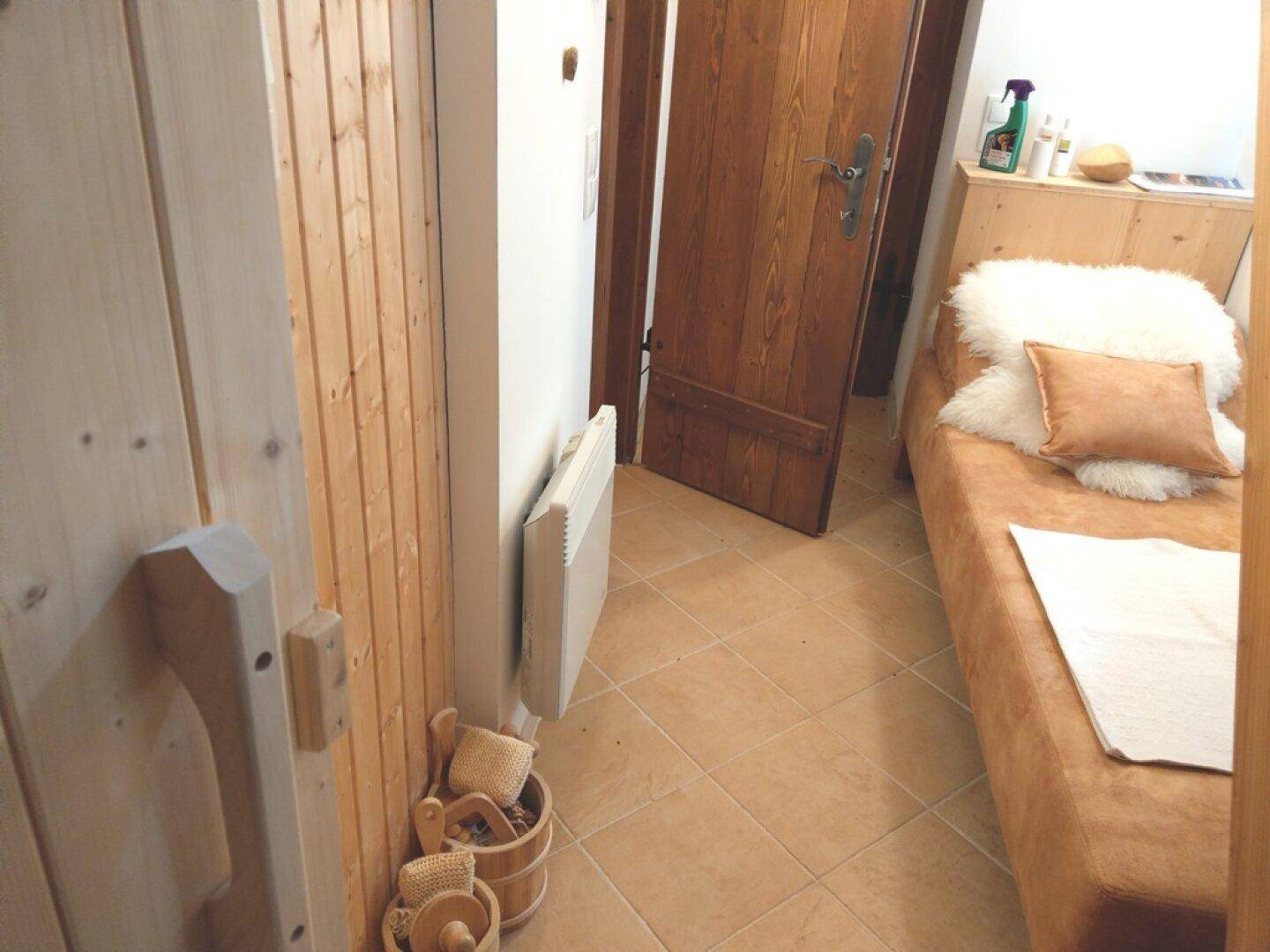 Kleines Schlafzimmer mit Einzelbett und Fliesenboden, neben der Sauna.